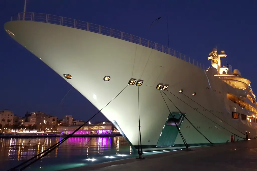 Bow of a superyacht moored in a marina at night