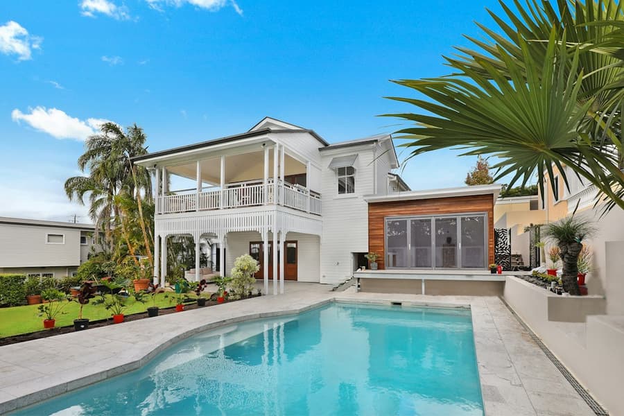 White two-story home with a pool and palms